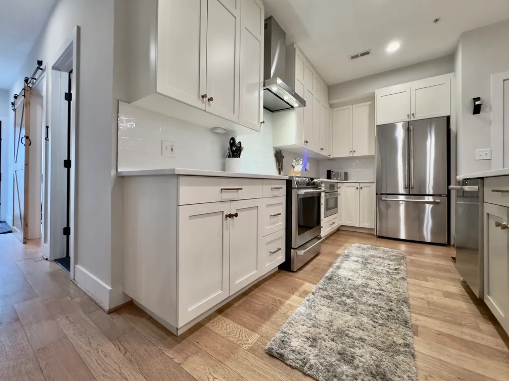 a kitchen with cabinets stainless steel appliances and a wooden floor