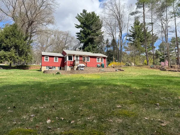 a sign board in front of a big yard with large trees