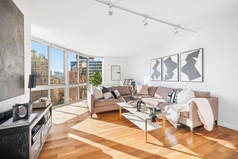 a living room with furniture a rug and a floor to ceiling window