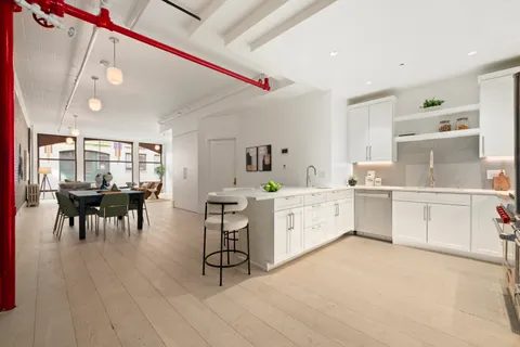 a large white kitchen with cabinets a sink and appliances