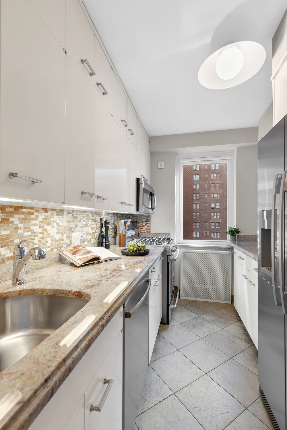 411 East 53rd Street, Unit 8C Manhattan, NY 10022 - Photo 4 of 10 a kitchen with a sink cabinets and window