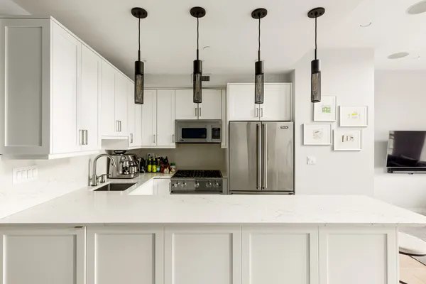 a kitchen with stainless steel appliances kitchen island granite countertop a refrigerator a oven and white cabinets