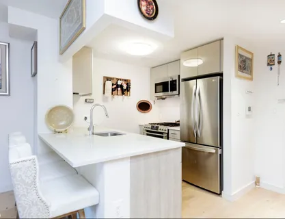 a kitchen with stainless steel appliances a refrigerator a sink a stove and white cabinets