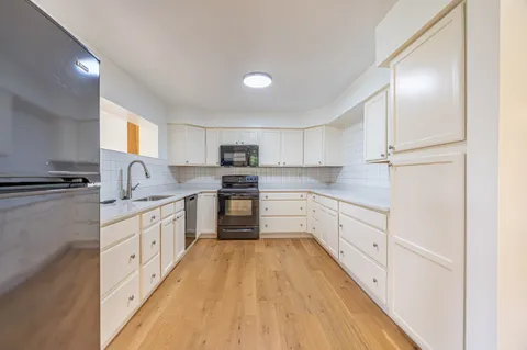 a kitchen with granite countertop white cabinets and white appliances