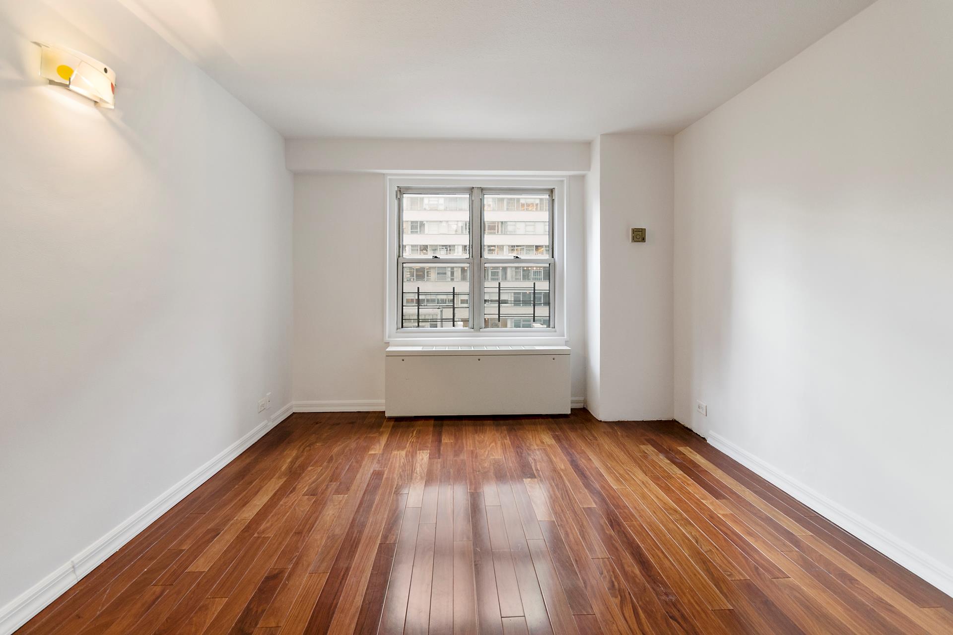 220 East 60th Street, Unit 7CD Manhattan, NY 10022 - Photo 6 of 11 an empty room with wooden floor and windows