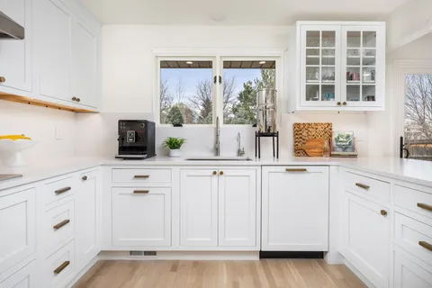 a kitchen with white cabinets and a window