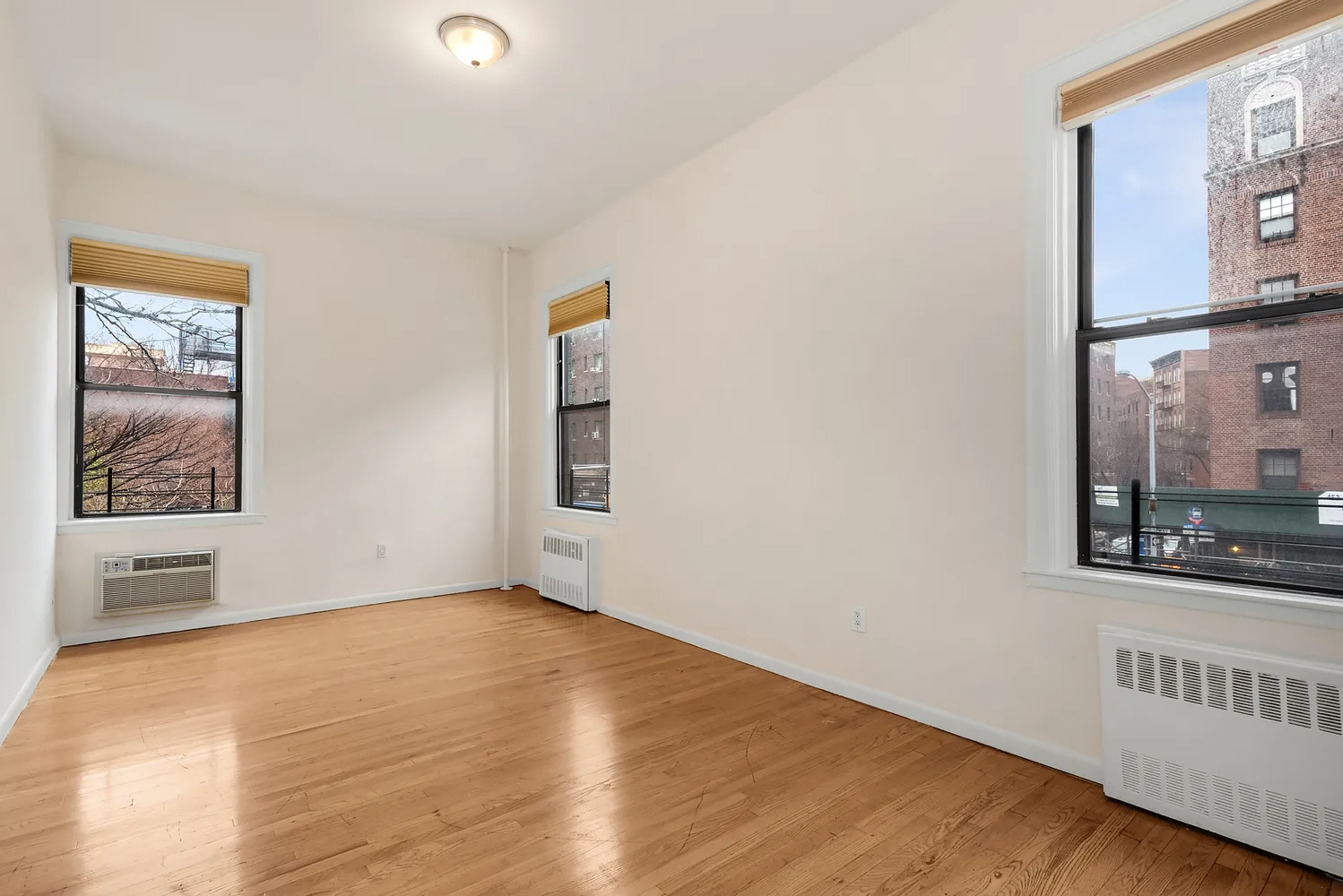 a view of an empty room with window and wooden floor
