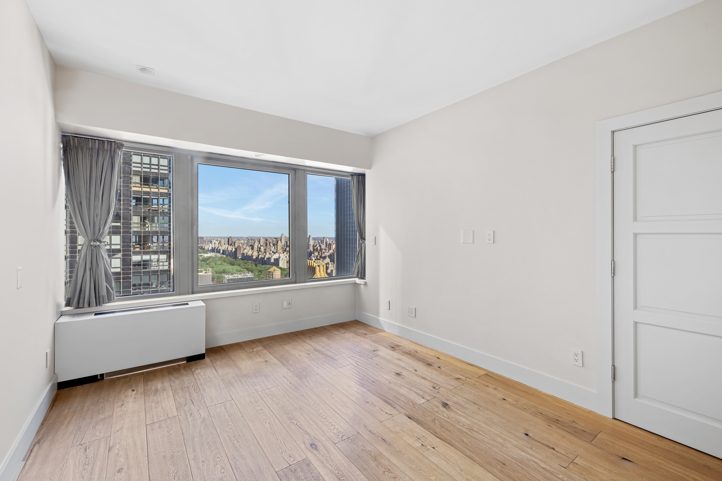 150 West 56th Street, Unit 4802 Manhattan, NY 10019 - Photo 7 of 13 an empty room with wooden floor and windows