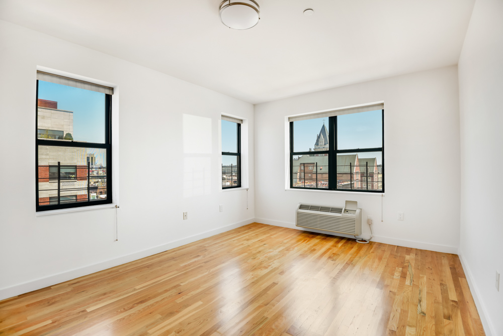 2098 Frederick Douglass Boulevard, Unit 7M Manhattan, NY 10026 - Photo 7 of 15 a view of an empty room with window and wooden floor