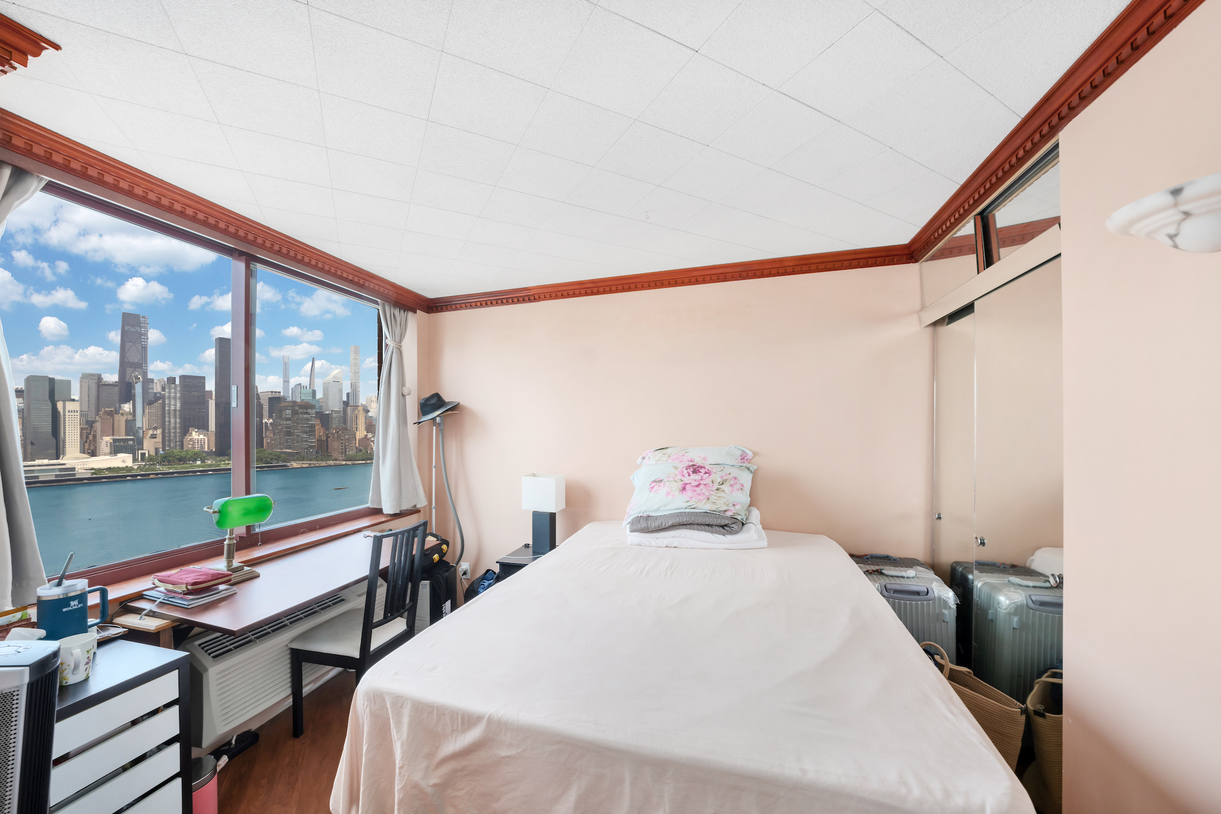 4-74 48th Avenue, Unit 27A Queens, NY 11109 - Photo 15 of 17 a bedroom with a bed and a large window with outer view