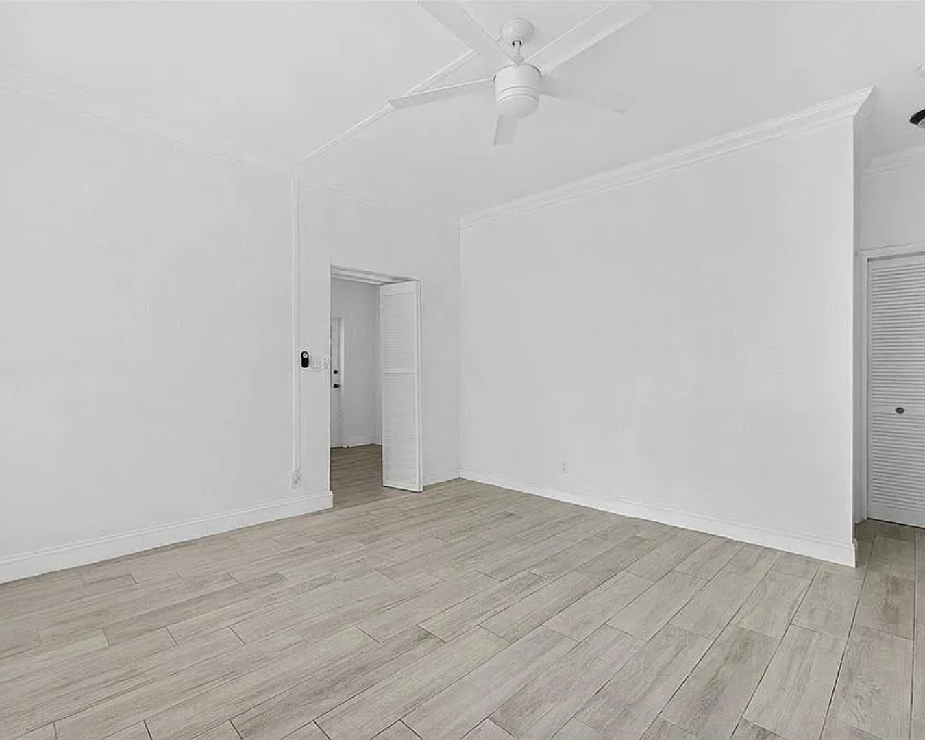 2822 Pine Tree Drive Miami Beach, FL 33140 - Photo 10 of 21 an empty room with wooden floor and fan