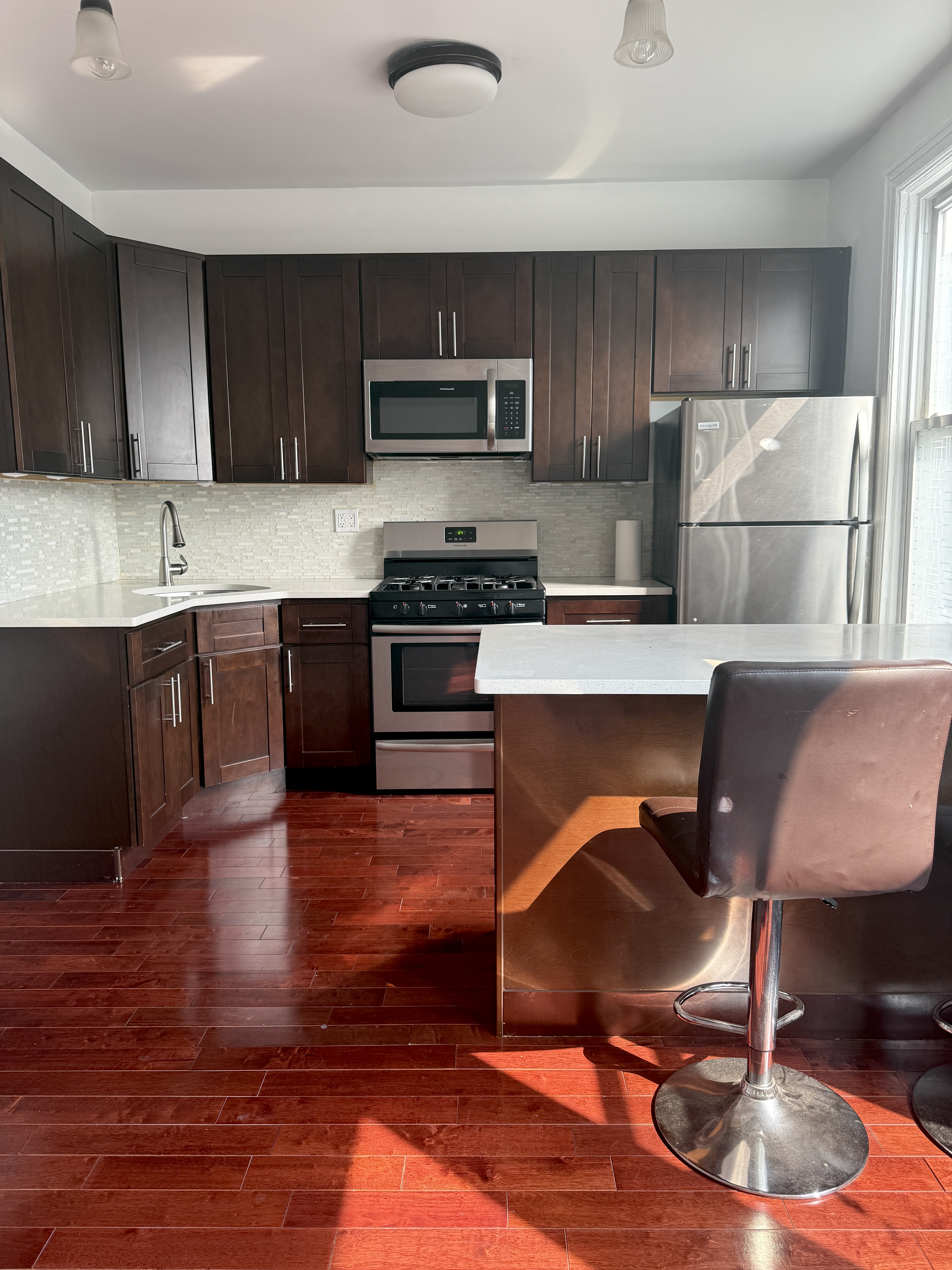 18-48 21st Drive, Unit 2R Queens, NY 11105 - Photo 2 of 7 a kitchen with wooden floors and wooden cabinets