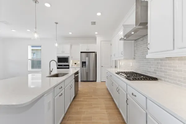 a large kitchen with stainless steel appliances kitchen island a large counter top a stove a sink a refrigerator and a counter top space