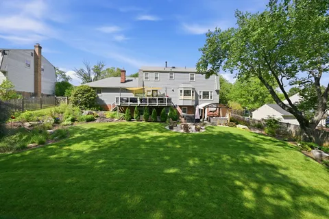 a view of a house with a big yard and large trees