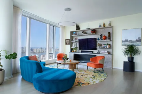 a living room with furniture a flat screen tv and a large window