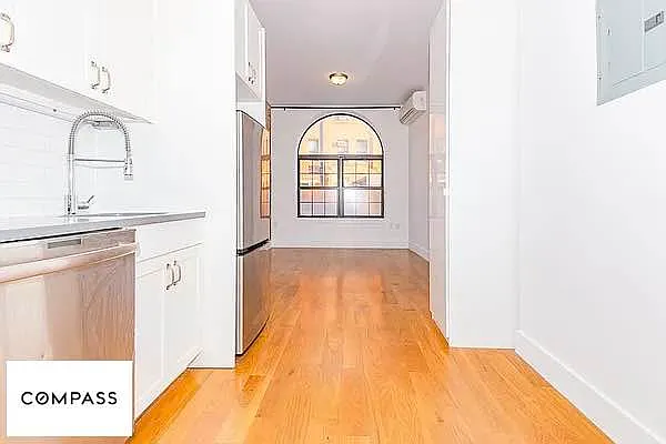 253 Stanhope Street, Unit 1B Brooklyn, NY 11237 - Photo 1 of 5 a large white kitchen with sink a window and stainless steel appliances