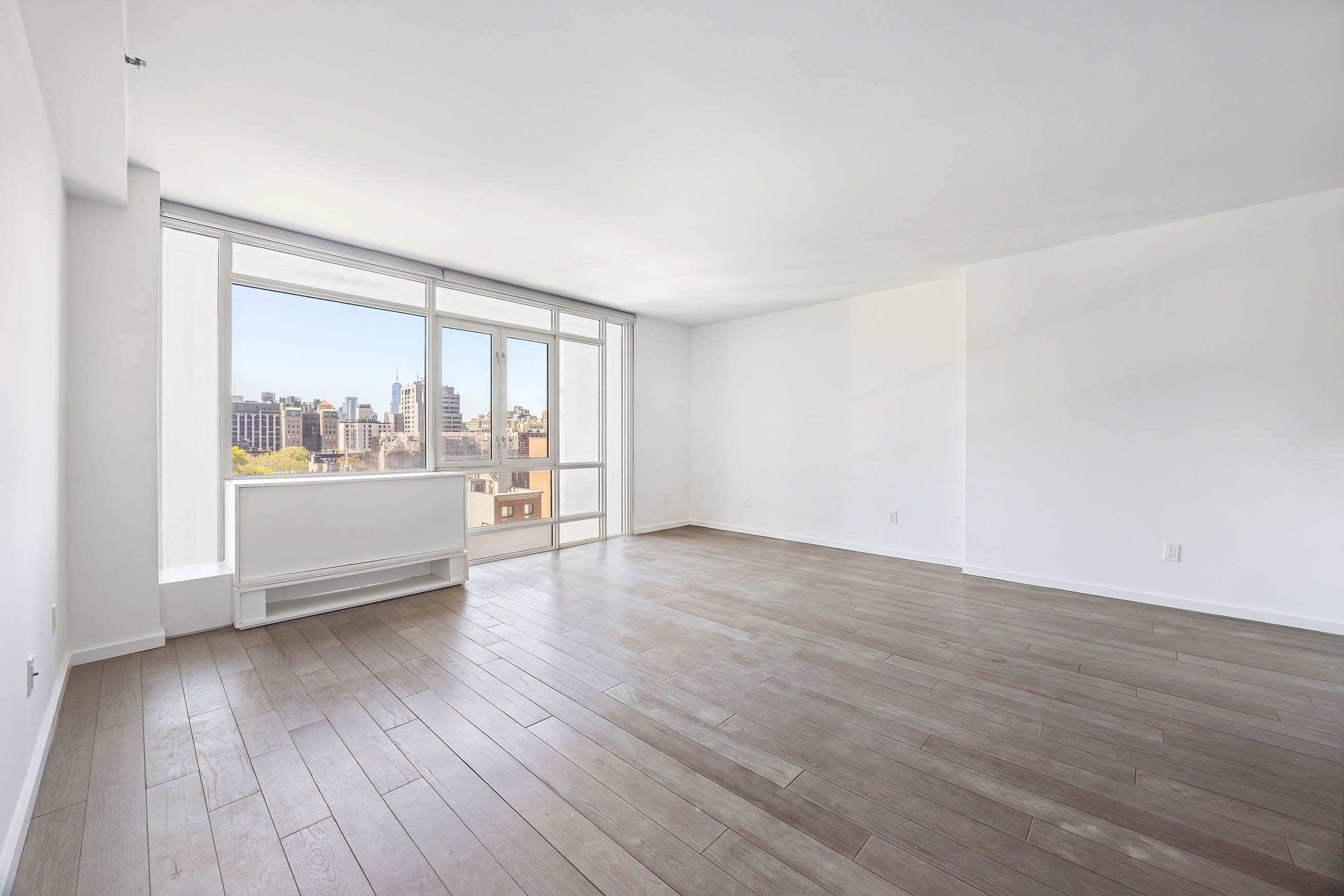 385 1st Avenue, Unit 10A Manhattan, NY 10010 - Photo 1 of 9 a view of an empty room with wooden floor and a window