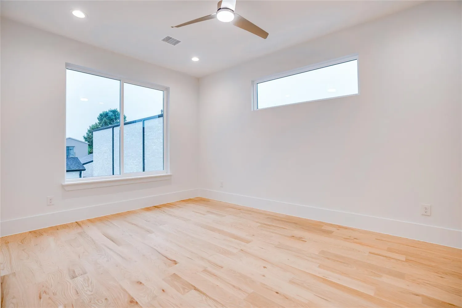 an empty room with wooden floor chandelier fan and windows
