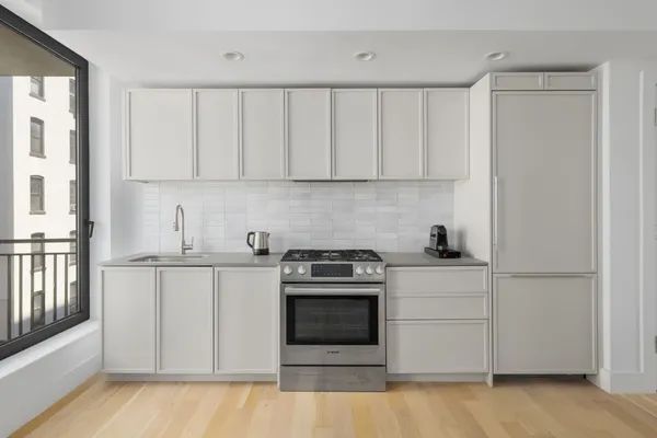 a kitchen with stainless steel appliances granite countertop a stove a sink and white cabinets
