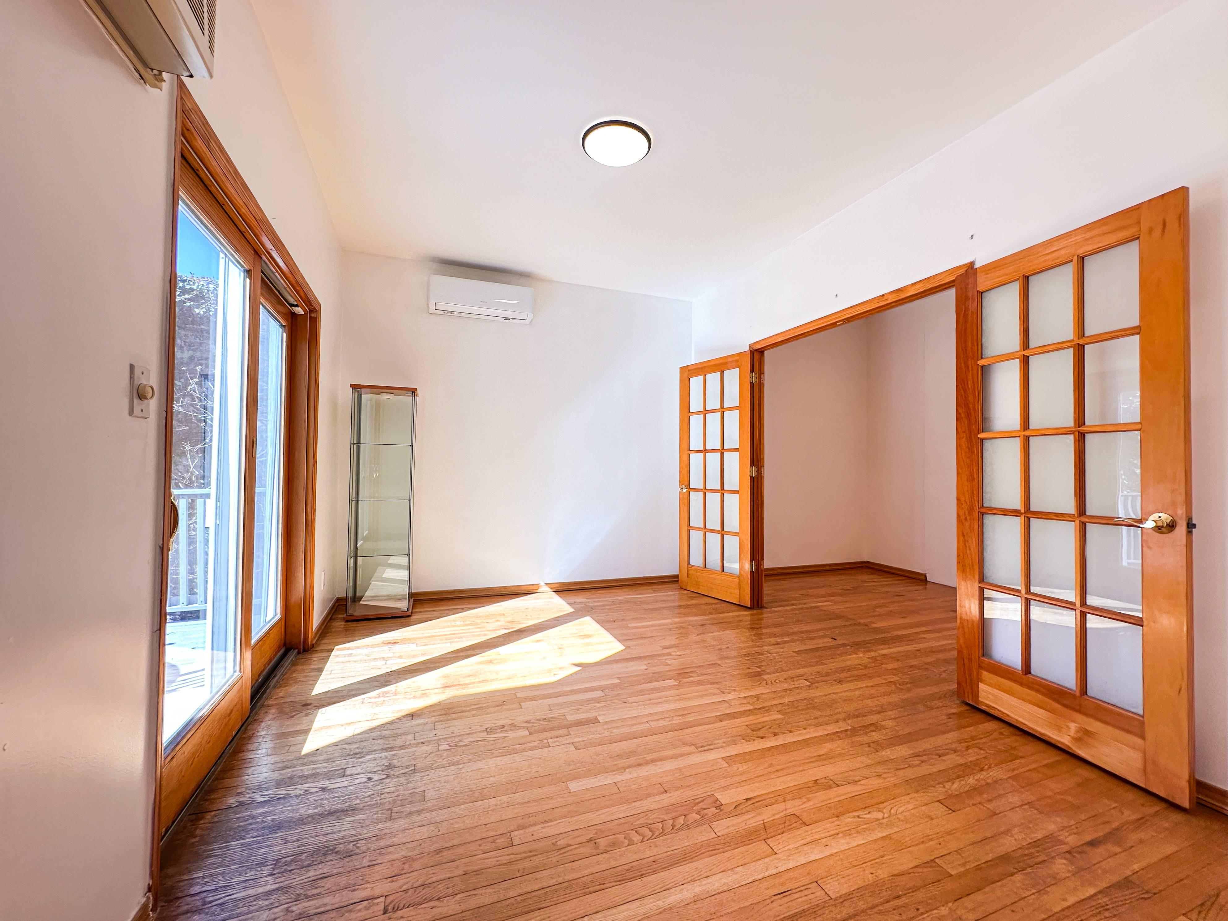 a view of an empty room with wooden floor and a window