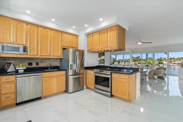a kitchen with stainless steel appliances granite countertop a stove top oven a sink a refrigerator and white cabinets