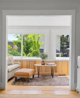 a living room with a floor to ceiling window and a wooden floor