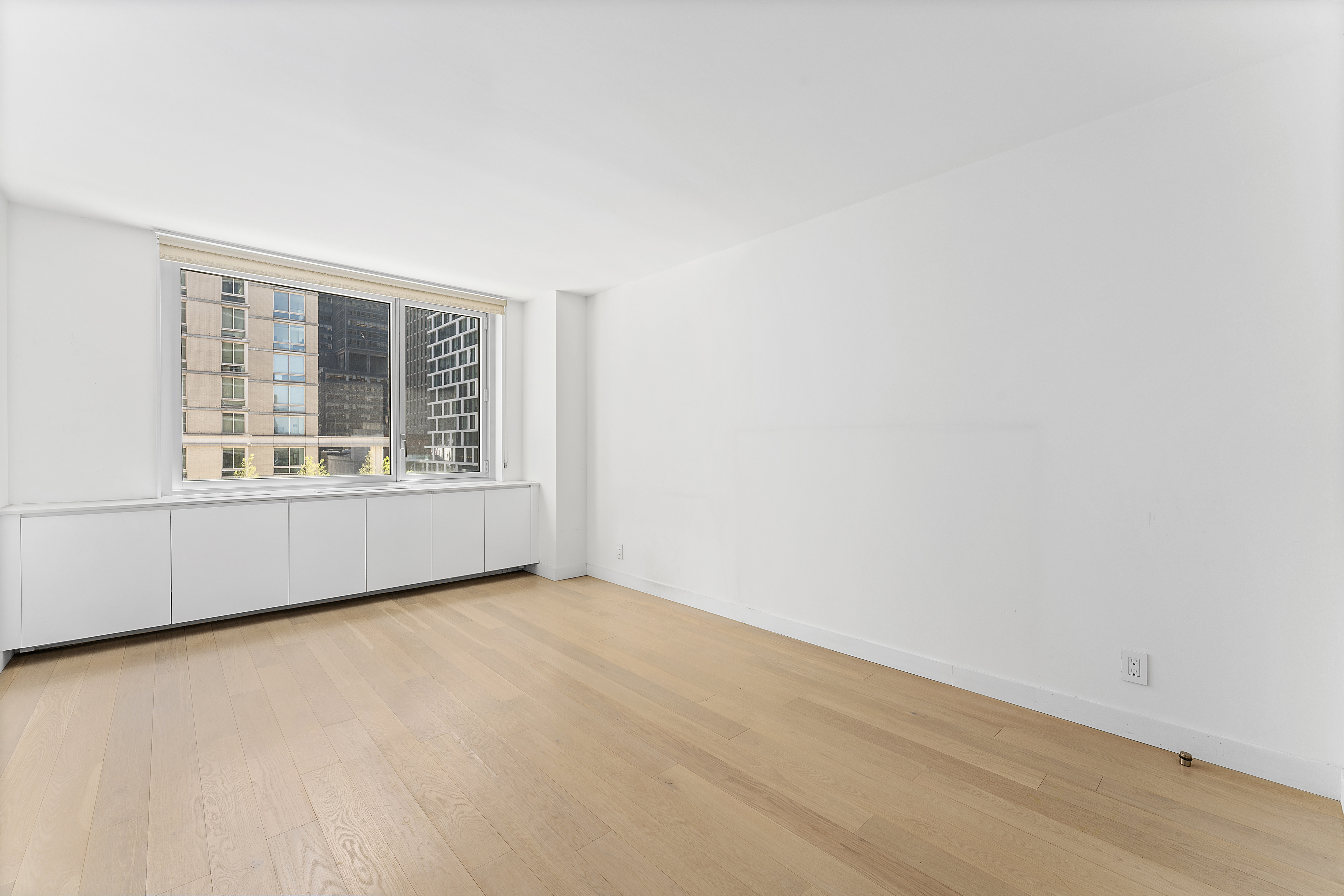 301 West 53rd Street, Unit 8J Manhattan, NY 10019 - Photo 6 of 14 an empty room with wooden floor and windows