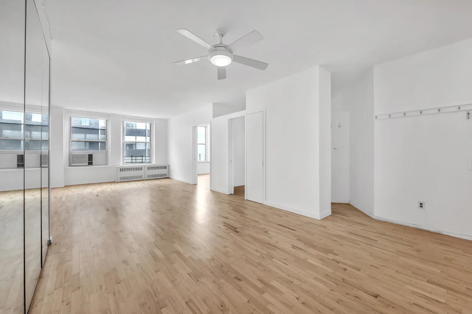 a view of an empty room with wooden floor and a window