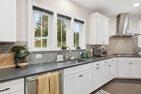 a kitchen with stainless steel appliances white cabinets and a window
