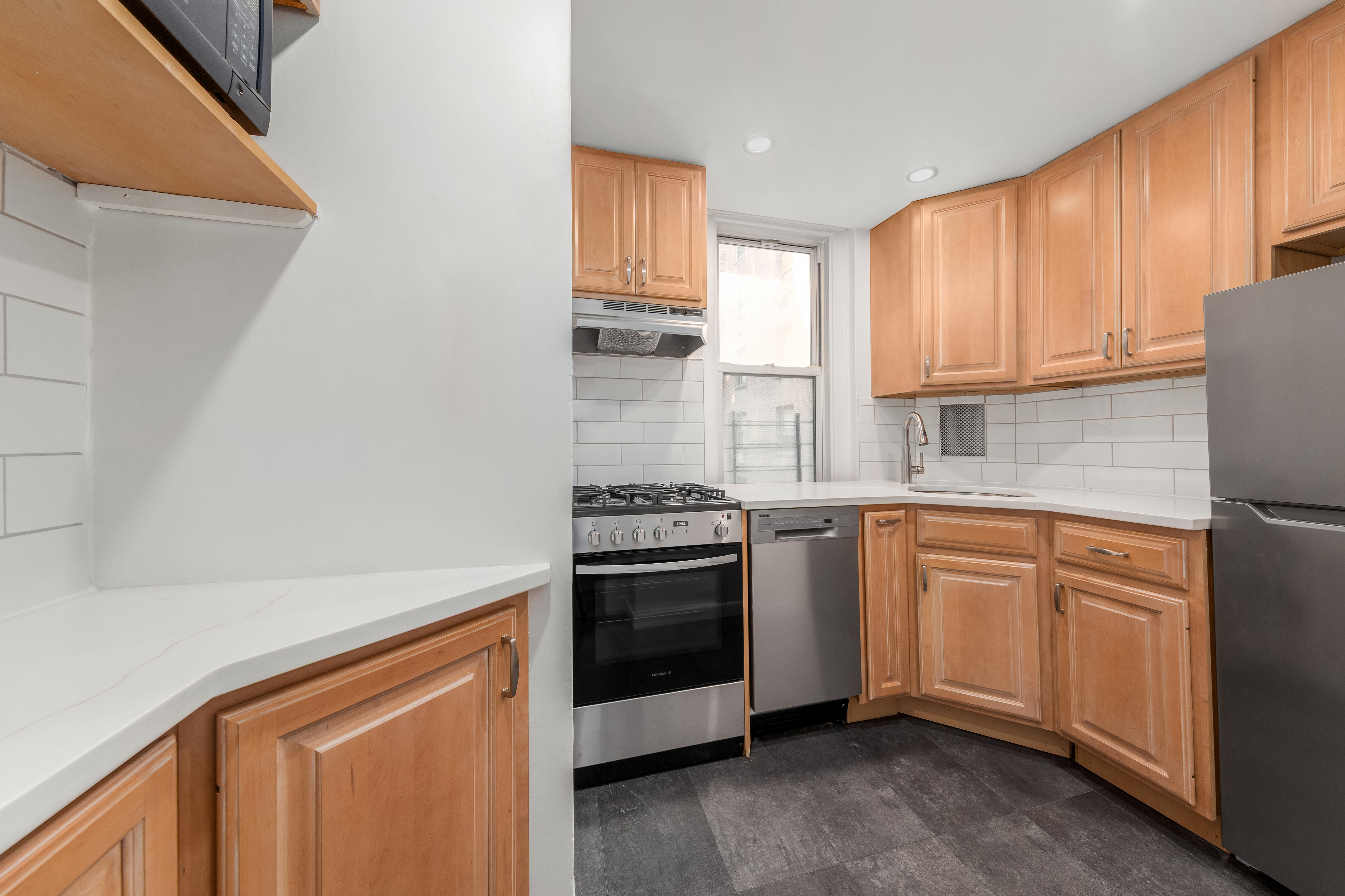 110 East 87th Street, Unit 5C Manhattan, NY 10128 - Photo 7 of 13 a kitchen with stainless steel appliances granite countertop a stove a sink and a microwave