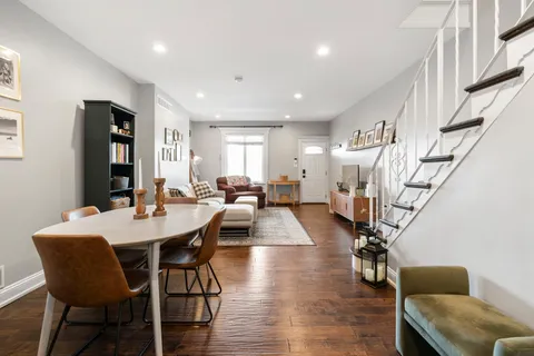 a view of dining room and livingroom with furniture wooden floor a rug a painting and a chandelier