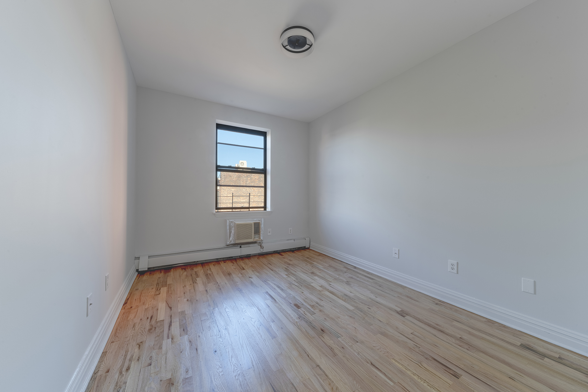 7 Mt Morris Park West, Unit D Manhattan, NY 10027 - Photo 9 of 16 an empty room with wooden floor and windows