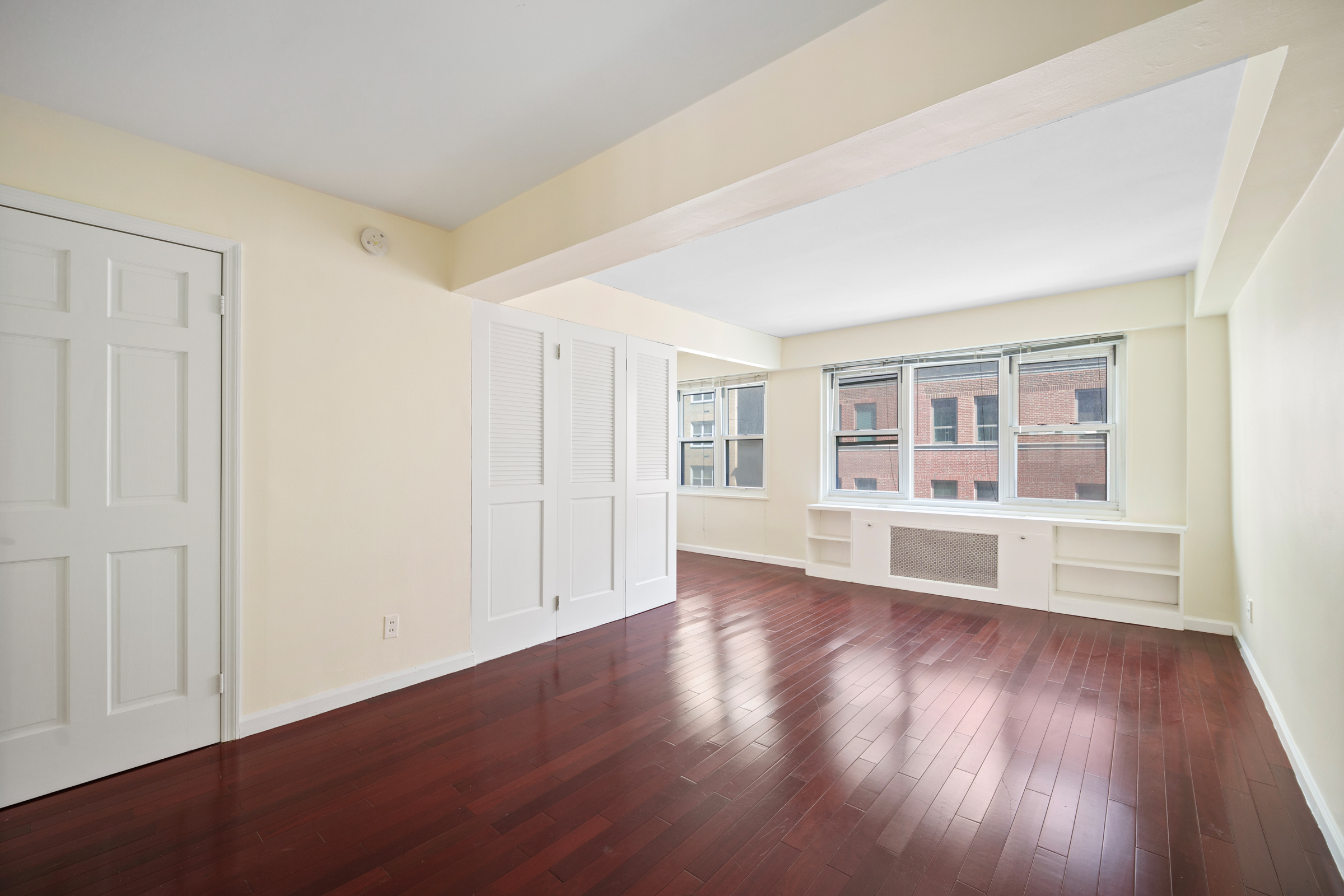 210 East 63rd Street, Unit 8C Manhattan, NY 10065 - Photo 5 of 12 a view of an empty room with wooden floor and a window