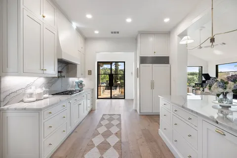 a large kitchen with stainless steel appliances kitchen island granite countertop a refrigerator and a sink