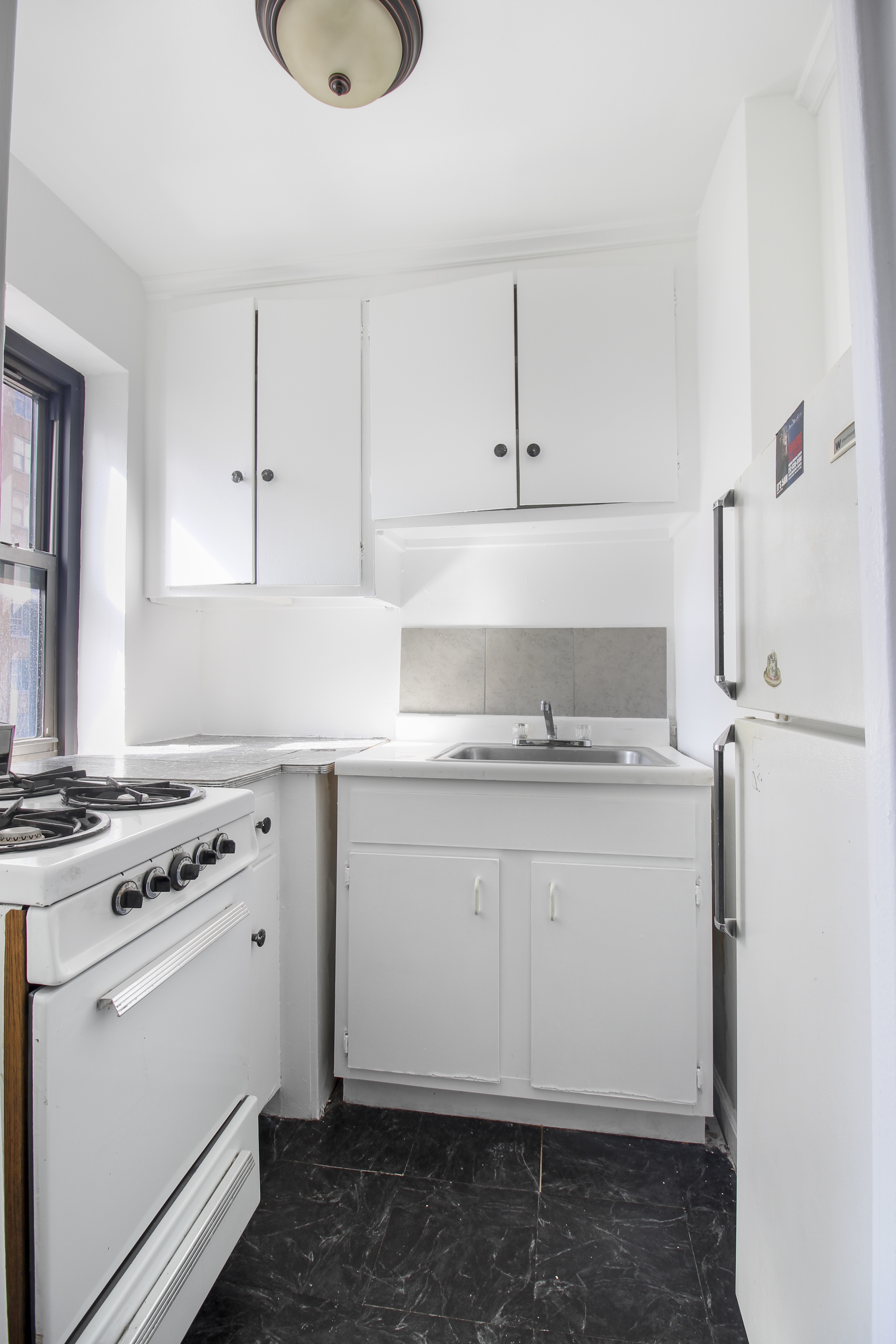 315 East 56th Street, Unit 5H Manhattan, NY 10022 - Photo 5 of 9 a kitchen with granite countertop white cabinets and white appliances