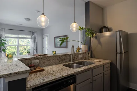 a kitchen with granite countertop a sink stainless steel appliances and window