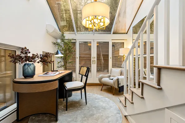 a view of a dining room with furniture a chandelier and a large window