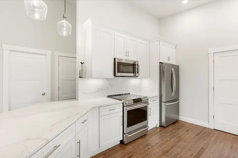 a kitchen with stainless steel appliances white cabinets and wooden floor
