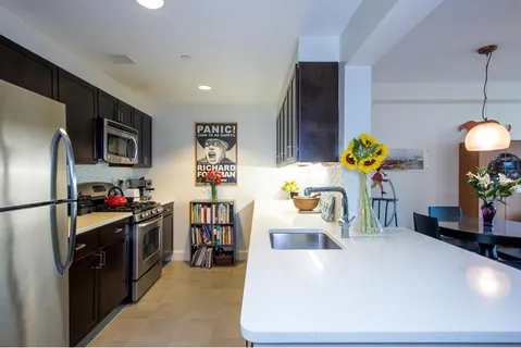 a kitchen with stainless steel appliances a stove a refrigerator a sink a counter space and wooden floor