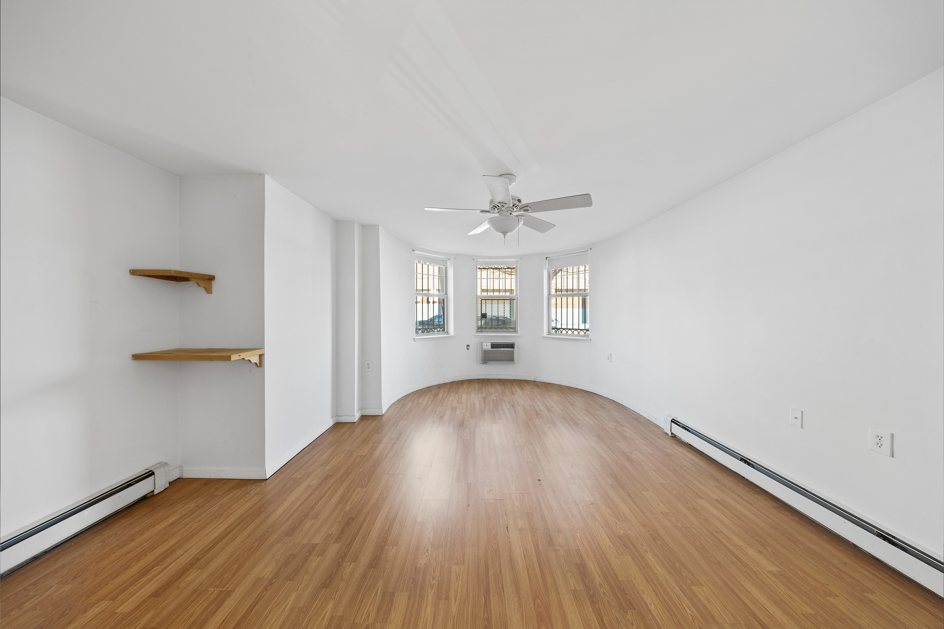 2028 Bergen Street, Unit 1 Brooklyn, NY 11233 - Photo 3 of 9 an empty room with wooden floor chandelier and windows