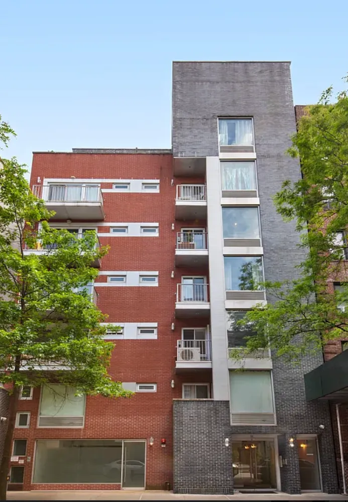 a front view of a building with a yard and plants