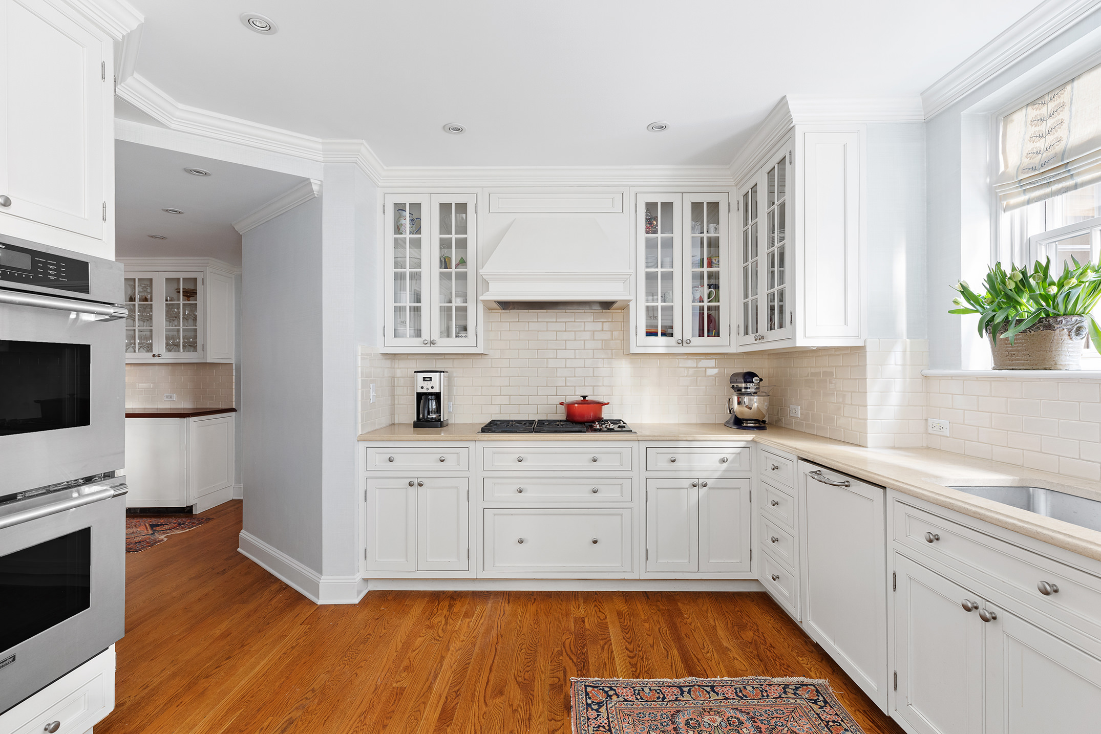 133 East 80th Street, Unit 3A Manhattan, NY 10075 - Photo 15 of 19 a kitchen with granite countertop a stove a sink dishwasher and white cabinets with wooden floor