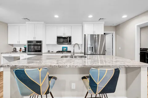 a kitchen with stainless steel appliances granite countertop a stove a sink a microwave a dining table and chairs