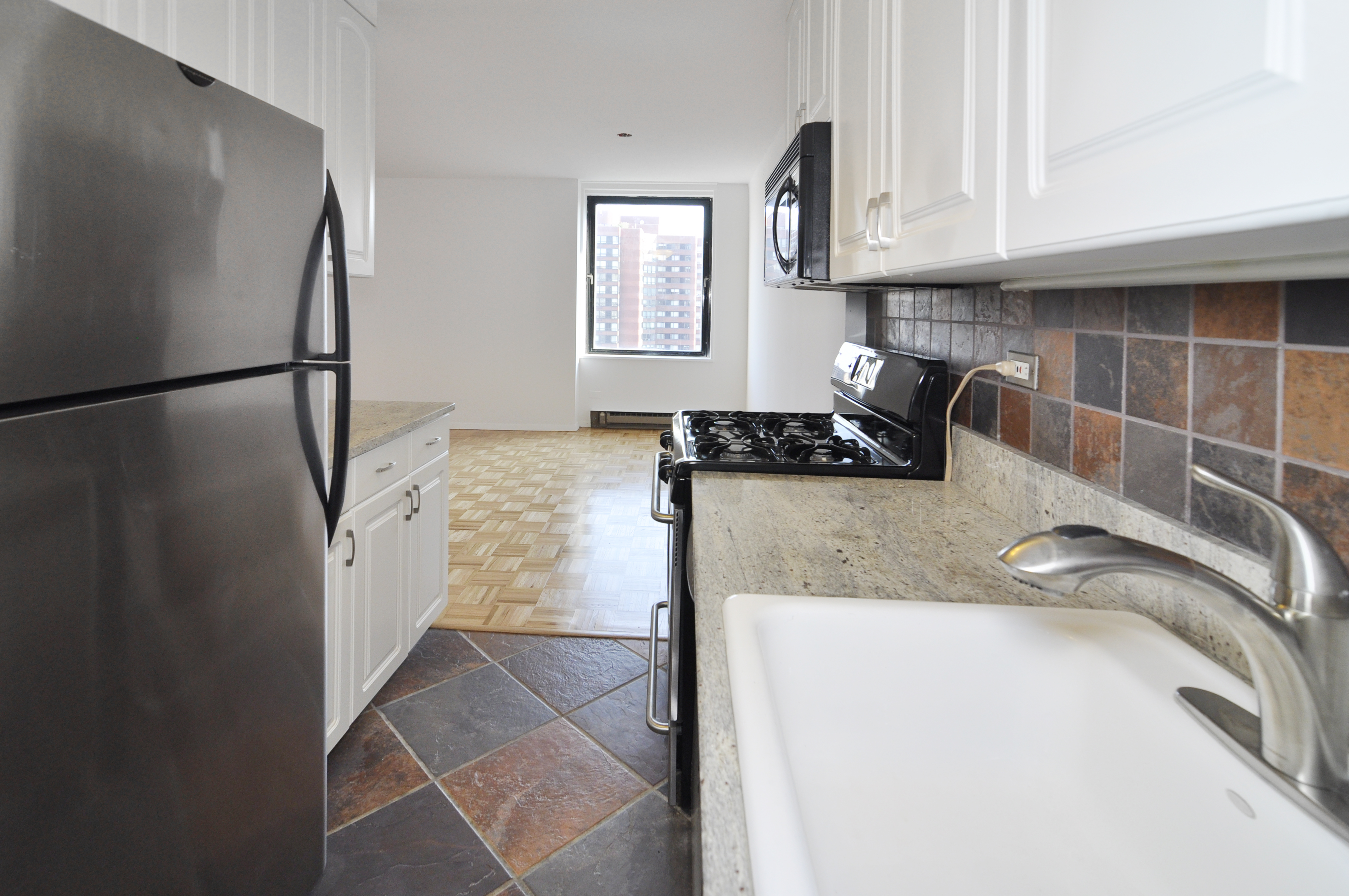 1623 3rd Avenue, Unit 25C Manhattan, NY 10128 - Photo 4 of 12 a kitchen with a refrigerator a stove a sink and a window