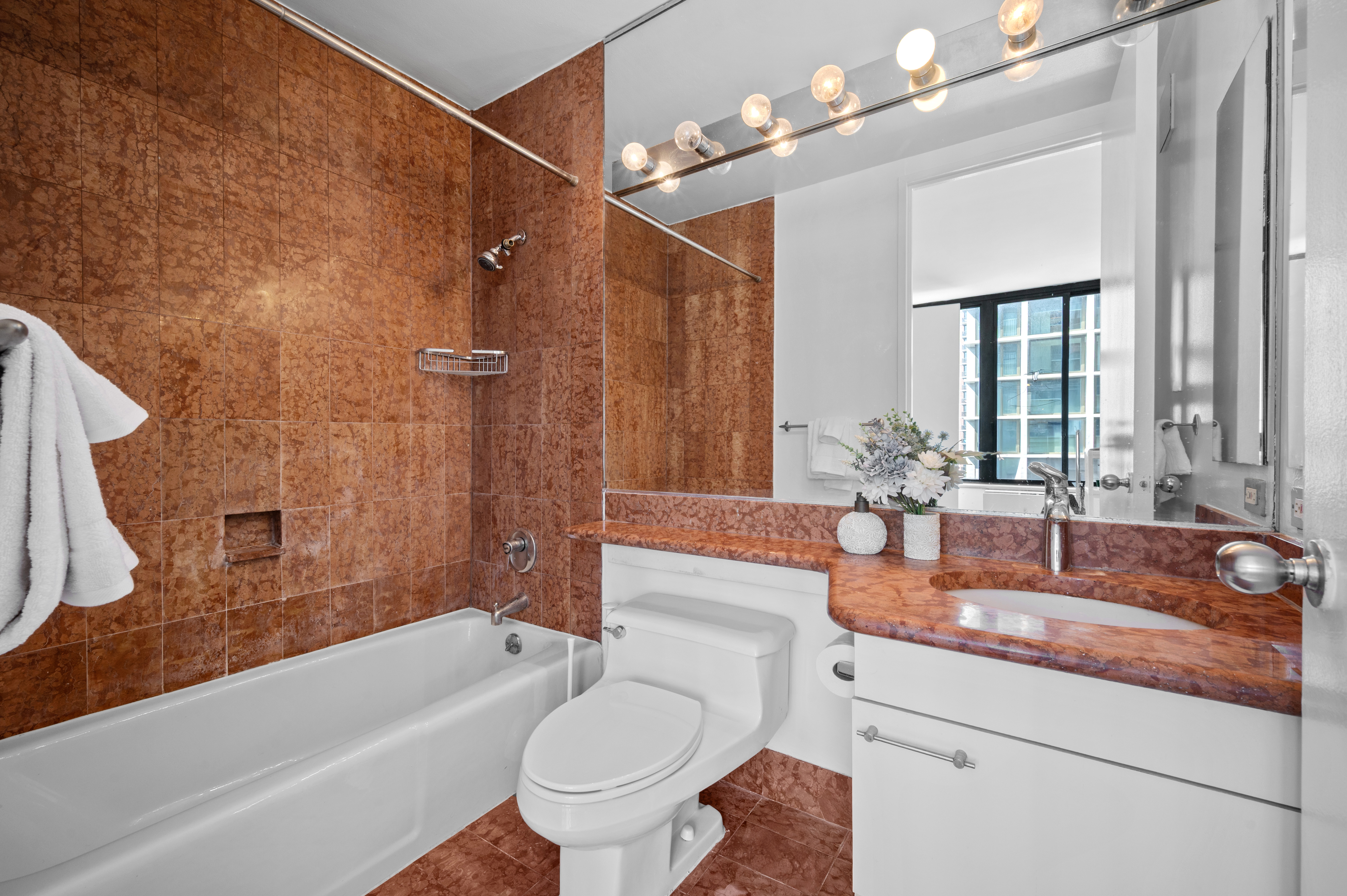 300 East 93rd Street, Unit 21C Manhattan, NY 10128 - Photo 6 of 6 a bathroom with a granite countertop sink a toilet a mirror and bathtub