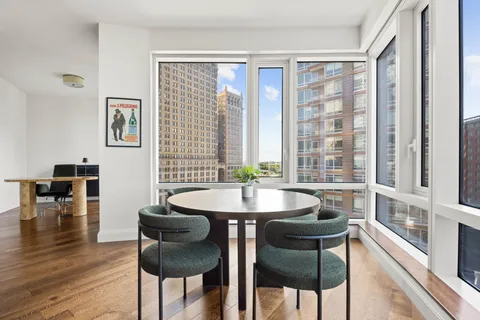 a dining room with wooden floor and a floor to ceiling window