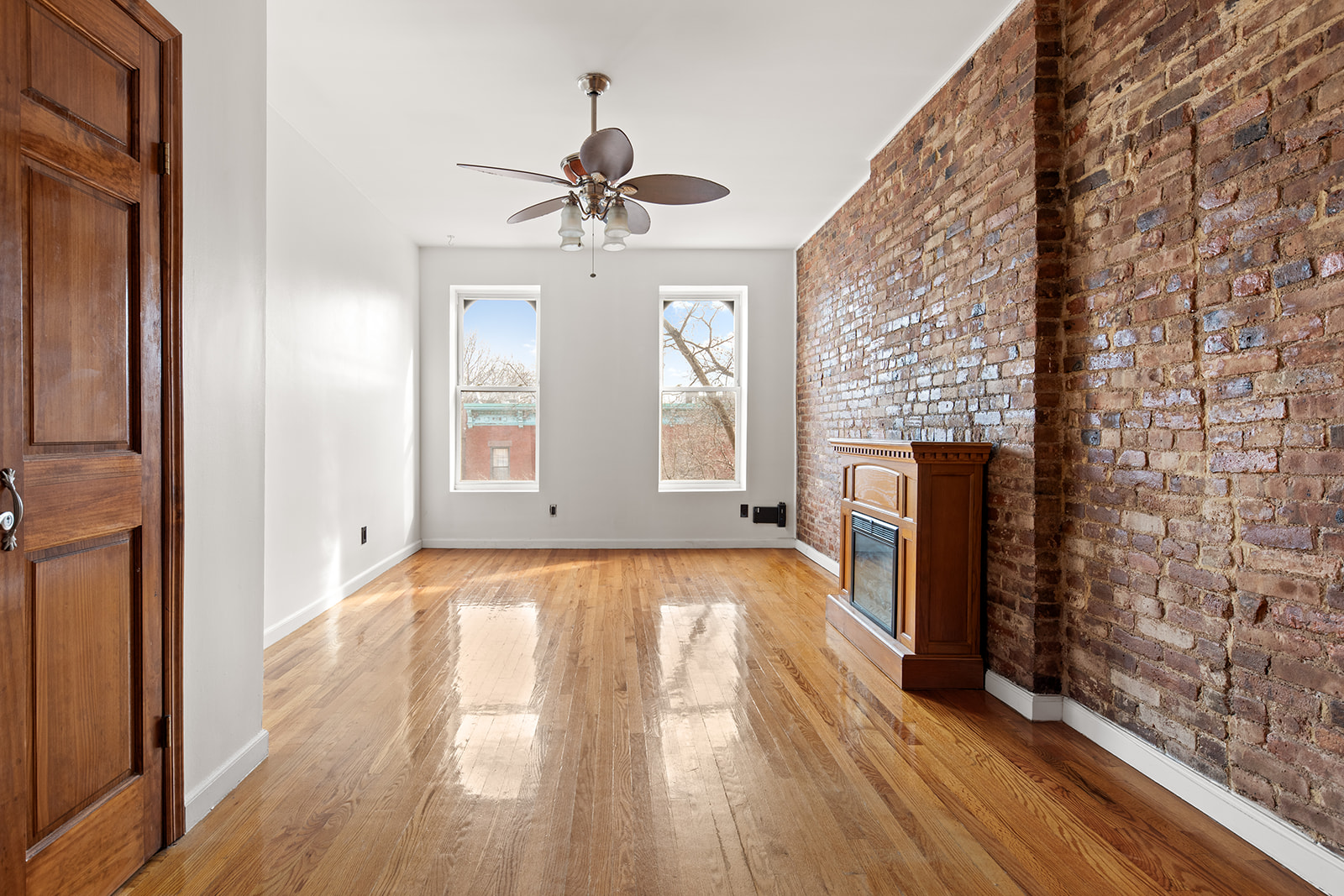 a view of an empty room with window and wooden floor