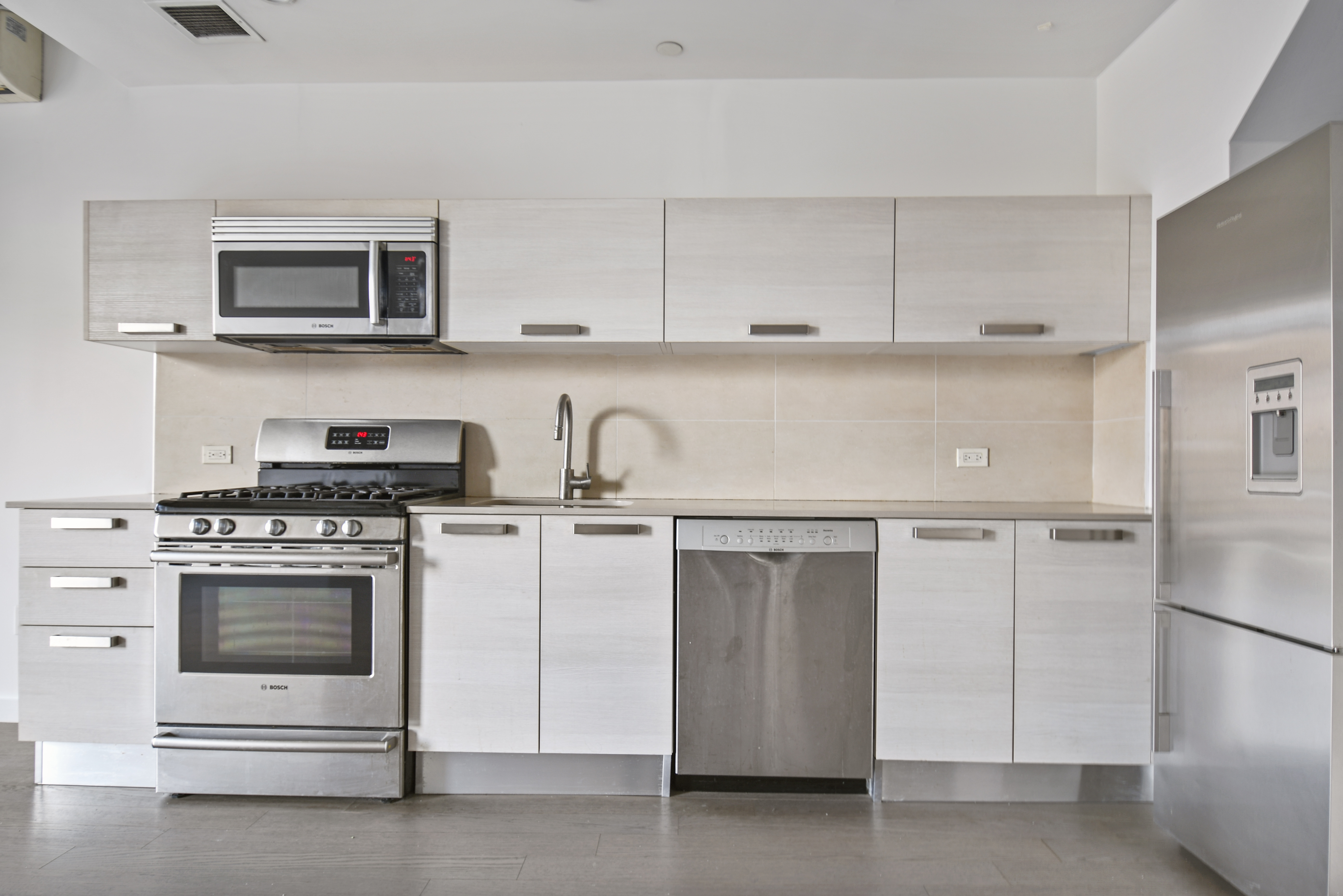 281 Union Avenue, Unit PHJ Brooklyn, NY 11211 - Photo 2 of 8 a kitchen with white cabinets and stainless steel appliances