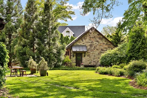 a backyard of a house with large trees and plants