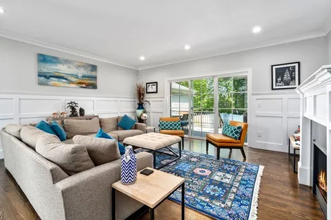 a living room with furniture a rug a lamp and a large window